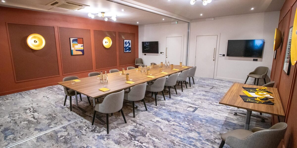 Hotel conference room with modern wooden meeting table and upholstered chairs supplied by DeFrae Contract Furniture.