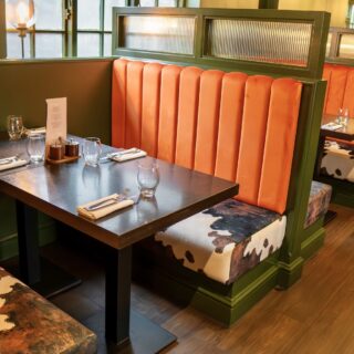 Straight run banquette seating supplied by DeFrae Contract Furniture for a steakhouse restaurant, featuring fluted back booths, solid wood tables, and Crib 5 contract upholstery.