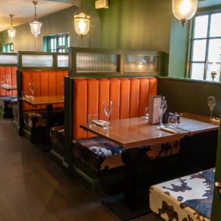 Straight run banquette seating supplied by DeFrae Contract Furniture for a steakhouse restaurant, featuring fluted back booths, solid wood tables, and Crib 5 contract upholstery.