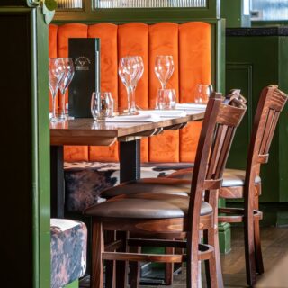 Restaurant chairs and solid wood tables supplied by DeFrae Contract Furniture, paired with fluted banquette seating and Crib 5 upholstery for a steakhouse dining space.