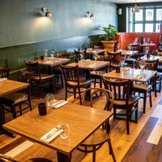 Restaurant furniture supplied by DeFrae Contract Furniture, featuring solid wood dining tables and contract chairs for a steakhouse and hospitality dining space.
