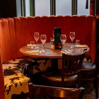 Curved banquette seating supplied by DeFrae Contract Furniture for a steakhouse restaurant, featuring fluted back upholstery, Crib 5 fabrics, and solid wood dining tables.