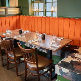 U shaped banquette seating supplied by DeFrae Contract Furniture for a steakhouse restaurant, featuring fluted back booths, solid wood tables, and Crib 5 contract upholstery.